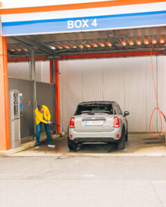 Mann wäscht Auto in der Waschbox.