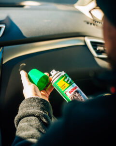 Mann sitzt im Auto mit Autoreiniger und putzt sein Auto.